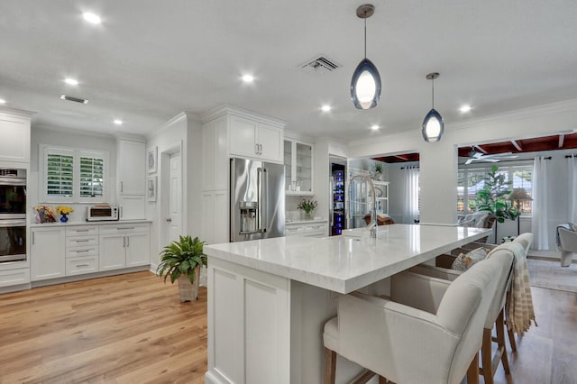 605 Flotilla Ln, North Palm Beach, FL 33408 - kitchen featuring appliances with stainless steel finishes, a sink, white cabinetry, a breakfast bar, and light wood-style floors