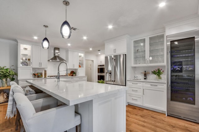 605 Flotilla Ln, North Palm Beach, FL 33408 - kitchen featuring wall chimney range hood, appliances with stainless steel finishes, wine cooler, white cabinetry, and recessed lighting