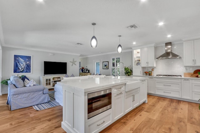 605 Flotilla Ln, North Palm Beach, FL 33408 - kitchen with stainless steel appliances, wall chimney range hood, ornamental molding, a sink, and white cabinets