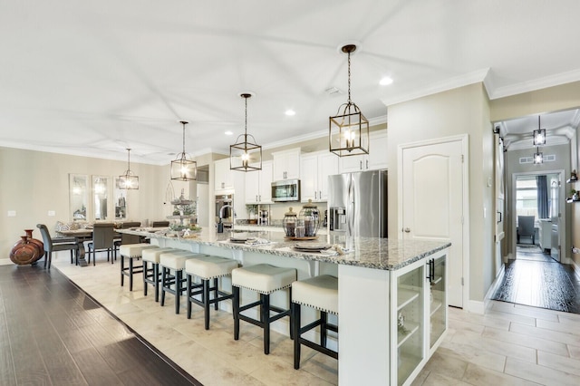 4052 SW Mccandless St, Port Saint Lucie, FL 34953 - kitchen with stainless steel appliances, a breakfast bar area, recessed lighting, ornamental molding, and white cabinets
