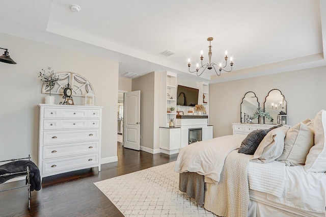 4052 SW Mccandless St, Port Saint Lucie, FL 34953 - bedroom with a chandelier, a tray ceiling, dark wood-style flooring, baseboards, and a glass covered fireplace