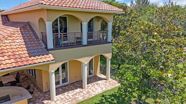 8380 Woodsmuir Dr, West Palm Beach, FL 33412 - view of side of property with a tiled roof, stucco siding, a balcony, and a patio
