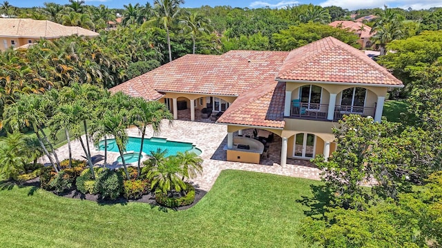 8380 Woodsmuir Dr, West Palm Beach, FL 33412 - rear view of house featuring stucco siding, an outdoor kitchen, a tile roof, a lawn, and a balcony