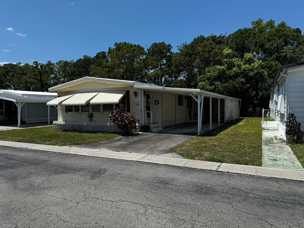 manufactured / mobile home featuring a front yard, driveway, an attached carport, and entry steps