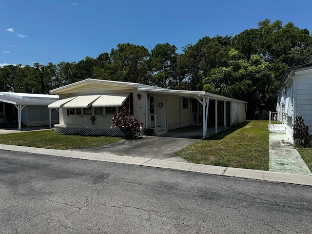 manufactured / mobile home featuring a front yard, driveway, an attached carport, and entry steps