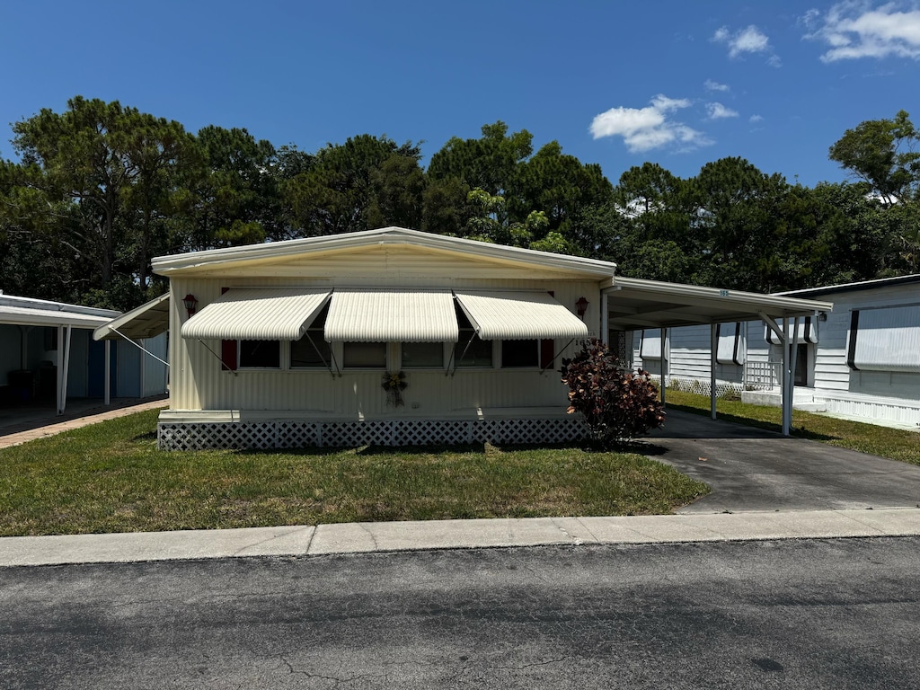 manufactured / mobile home with asphalt driveway, a carport, and a front yard