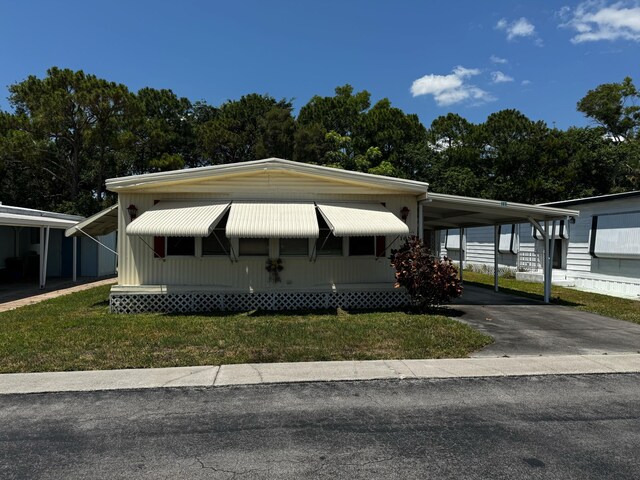 manufactured / mobile home with asphalt driveway, a carport, and a front yard