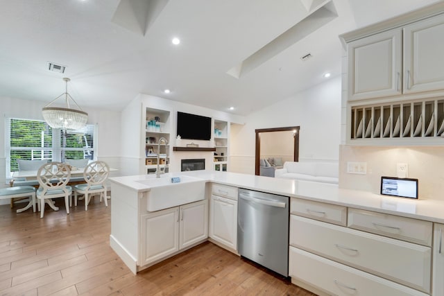 kitchen with dishwasher, a glass covered fireplace, open floor plan, light countertops, and vaulted ceiling