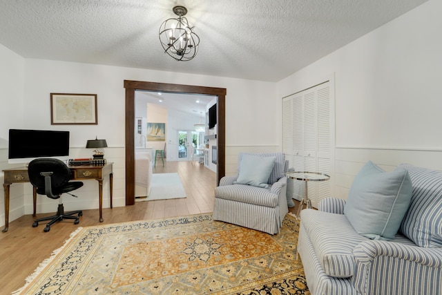 office space featuring wood finished floors, a textured ceiling, a wainscoted wall, and a chandelier