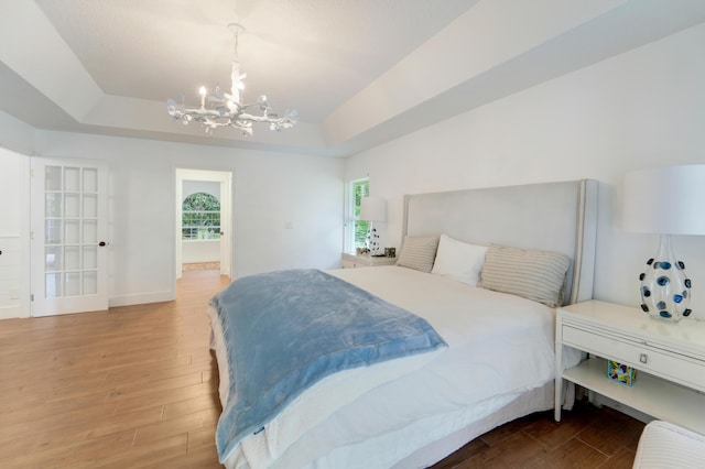 bedroom with a chandelier, wood finished floors, and baseboards