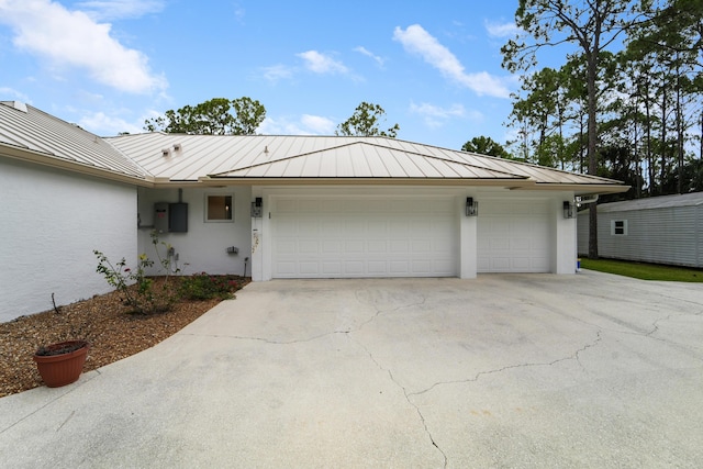 view of front of home with a standing seam roof, a garage, driveway, stucco siding, and metal roof