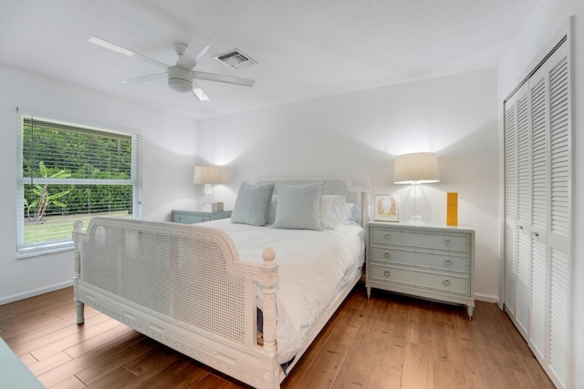bedroom featuring baseboards, wood finished floors, a ceiling fan, and a closet