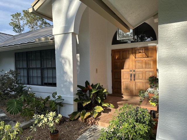 doorway to property featuring metal roof, stucco siding, and a standing seam roof