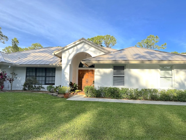 ranch-style house with stucco siding, a front lawn, metal roof, and a standing seam roof