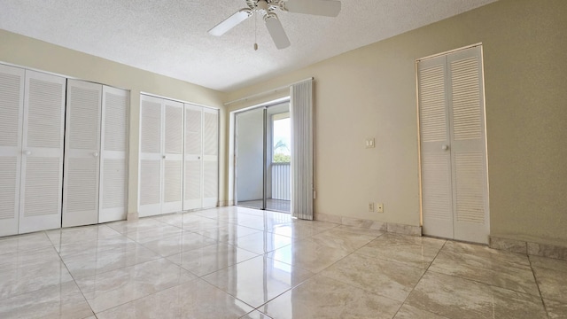 unfurnished bedroom with two closets, a textured ceiling, a ceiling fan, and baseboards