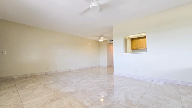 spare room with ceiling fan, light marble finish flooring, and baseboards