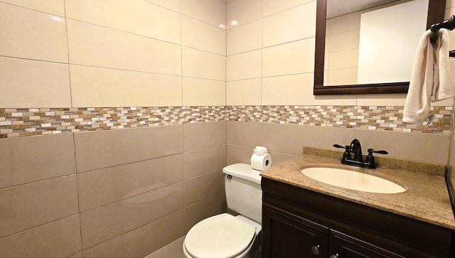 half bath with toilet, vanity, and tile walls