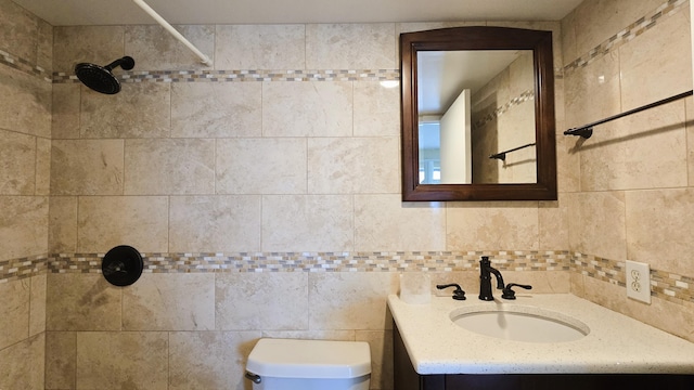 bathroom featuring toilet, vanity, tiled shower, and tile walls