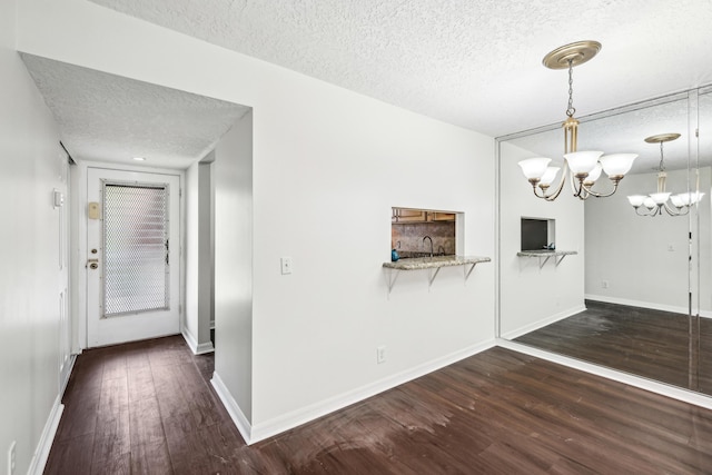 12012 Greenway Cir S Unit 206, Royal Palm Beach, FL 33411 - unfurnished dining area with a textured ceiling, dark wood finished floors, a chandelier, baseboards, and a sink