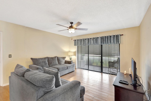 living area with a ceiling fan, light wood finished floors, and a textured ceiling