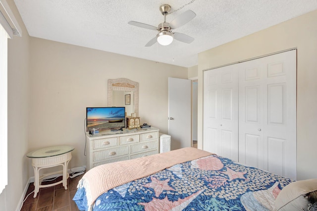 bedroom featuring a closet, dark wood-style floors, ceiling fan, baseboards, and a textured ceiling