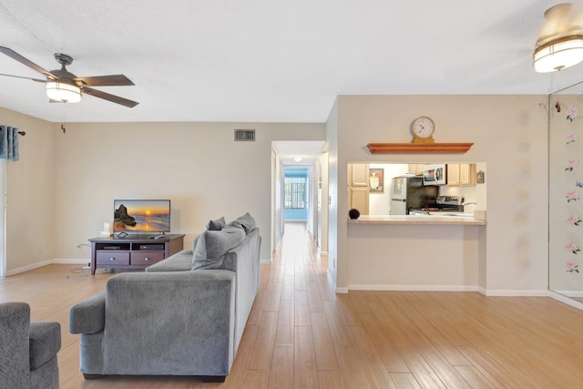 living area featuring light wood finished floors, ceiling fan, and baseboards