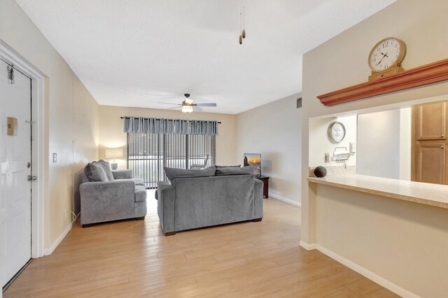 living room featuring ceiling fan, light wood-type flooring, and baseboards