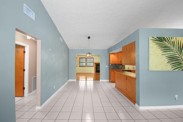 895 SE Waterside Way, Stuart, FL 34997 - kitchen with decorative backsplash, light tile patterned floors, brown cabinetry, baseboards, and a textured ceiling
