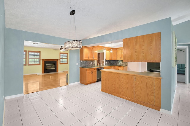 895 SE Waterside Way, Stuart, FL 34997 - kitchen with open floor plan, dishwasher, light tile patterned flooring, tasteful backsplash, and a fireplace with flush hearth