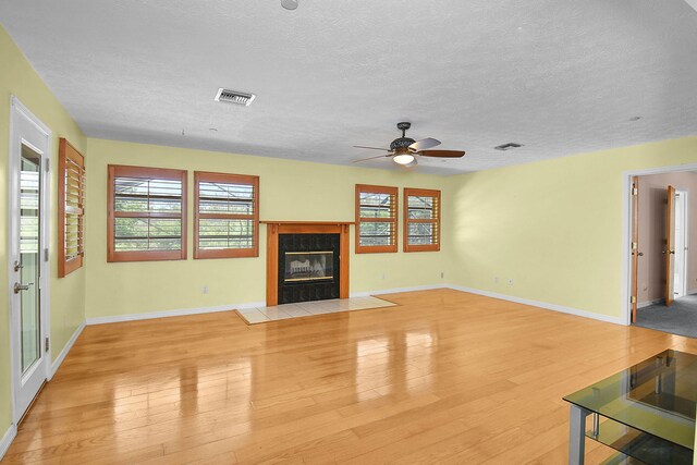 895 SE Waterside Way, Stuart, FL 34997 - unfurnished living room featuring a textured ceiling, ceiling fan, light wood finished floors, a fireplace, and baseboards