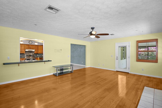 895 SE Waterside Way, Stuart, FL 34997 - unfurnished living room featuring wood finished floors, ceiling fan, a sink, baseboards, and a textured ceiling