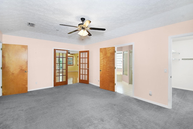 895 SE Waterside Way, Stuart, FL 34997 - unfurnished bedroom with french doors, carpet flooring, a spacious closet, a textured ceiling, and baseboards