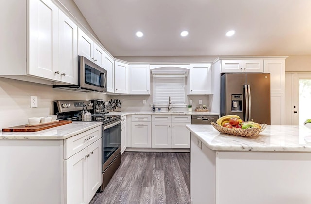 kitchen featuring stainless steel appliances, a sink, dark wood finished floors, white cabinets, and light stone counters