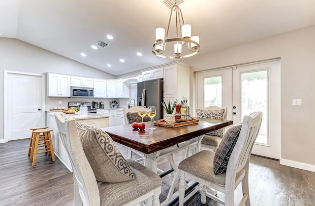 dining space featuring vaulted ceiling, dark wood-type flooring, a chandelier, french doors, and baseboards
