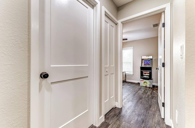 hallway featuring dark wood finished floors, baseboards, and a textured wall