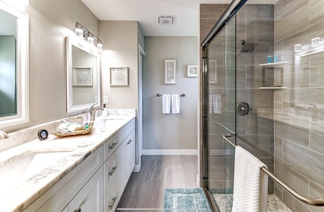 full bath featuring a stall shower and double vanity