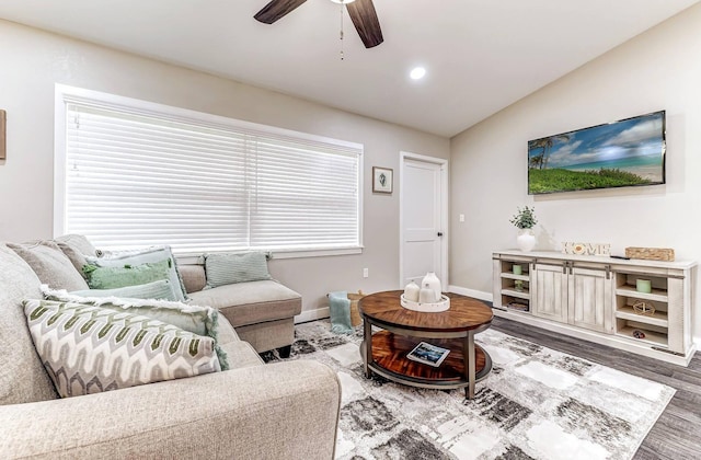 living area with ceiling fan, wood finished floors, baseboards, lofted ceiling, and plenty of natural light
