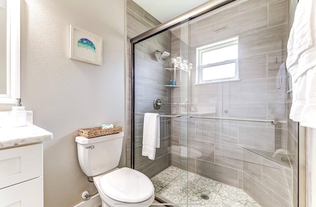 full bathroom featuring vanity, a shower stall, and toilet