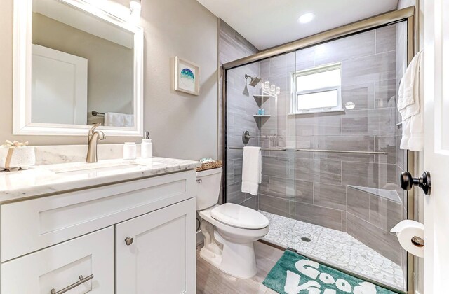 full bathroom featuring a stall shower, vanity, toilet, and wood finished floors