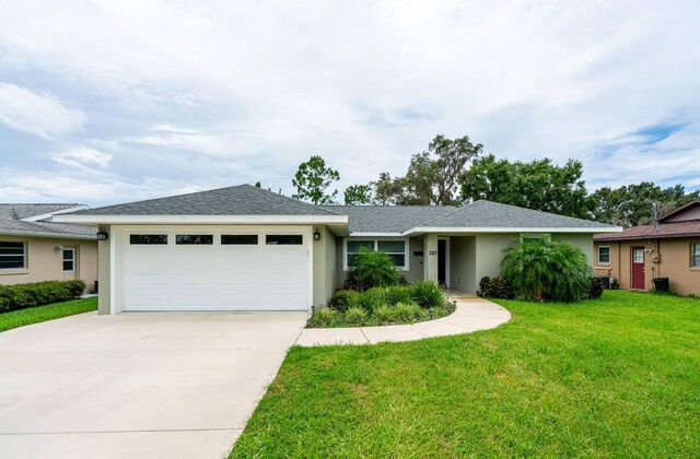ranch-style house featuring a garage, concrete driveway, stucco siding, and a front yard