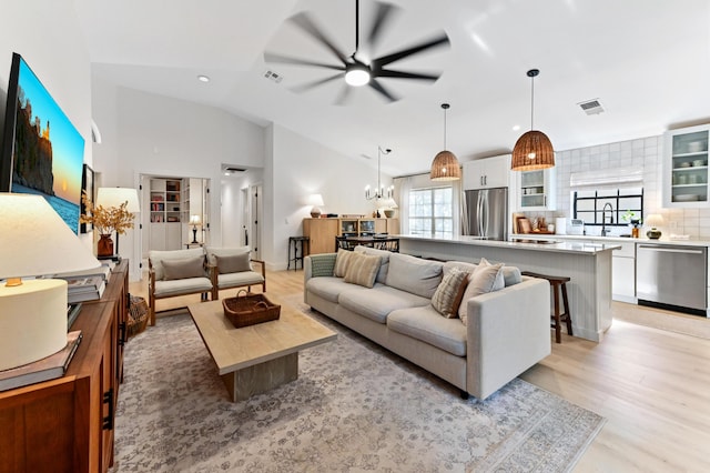 living area featuring a ceiling fan, light wood-style floors, vaulted ceiling, recessed lighting, and a chandelier