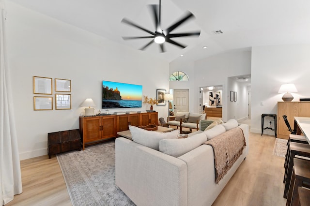 living room featuring a ceiling fan, light wood-style flooring, high vaulted ceiling, and baseboards
