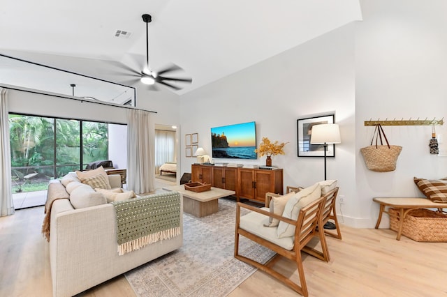 living room with light wood-type flooring, ceiling fan, high vaulted ceiling, and baseboards