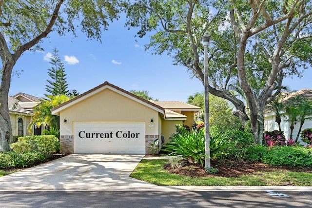 view of front of property featuring an attached garage, concrete driveway, stucco siding, and a tiled roof