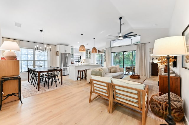 living area with ceiling fan, a chandelier, light wood finished floors, and vaulted ceiling