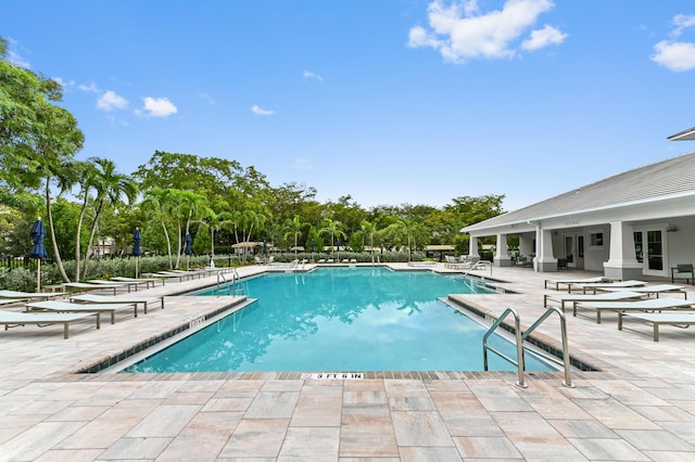 community pool with a patio area and view of scattered trees