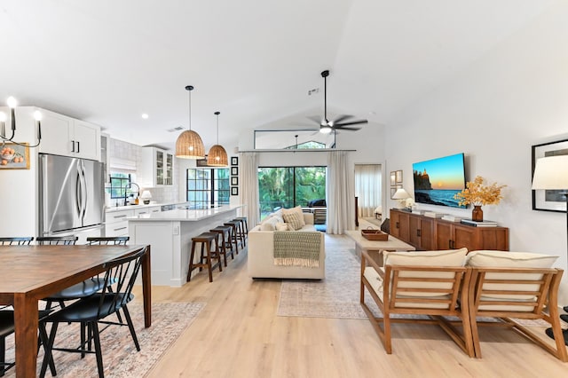 living area with light wood-type flooring, a ceiling fan, and high vaulted ceiling