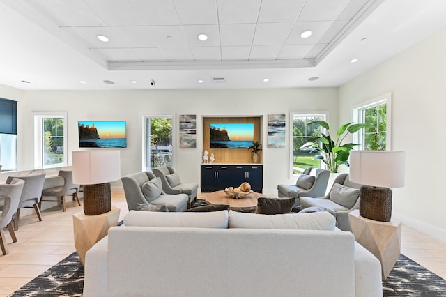 living area with a raised ceiling, recessed lighting, baseboards, and light wood finished floors