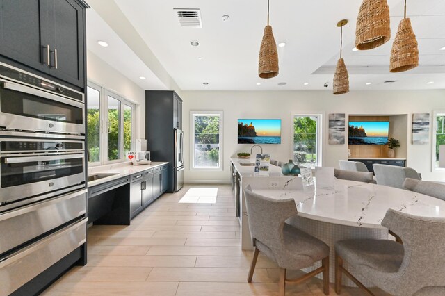 kitchen with dark cabinetry, a kitchen breakfast bar, appliances with stainless steel finishes, light stone countertops, and recessed lighting