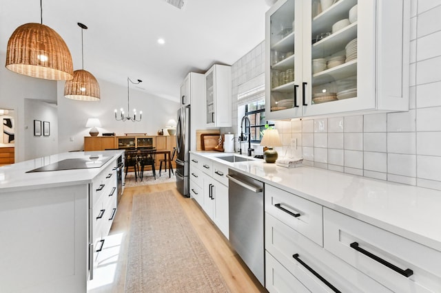 kitchen with appliances with stainless steel finishes, light wood-style flooring, backsplash, a center island, and a sink